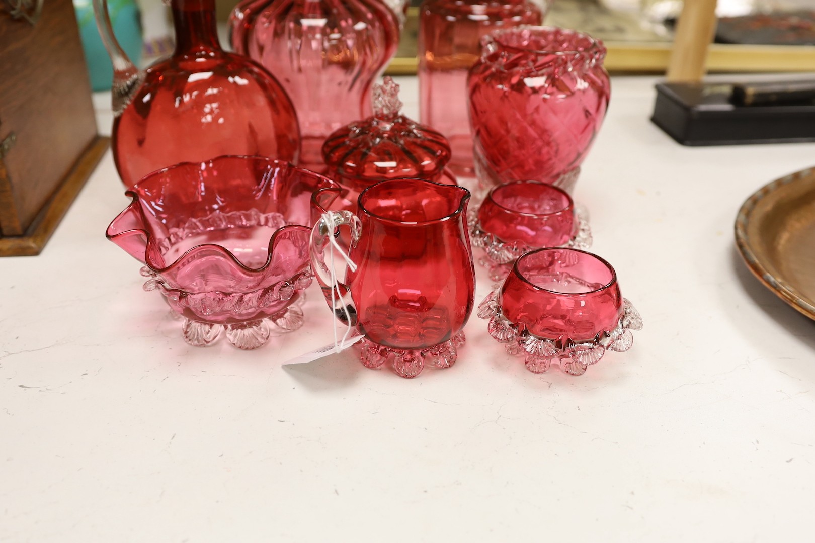 Two tall Victorian cranberry glass jugs, a decanter, a powder bowl ad four other items, tallest item decanter and stopper 27 cms high.